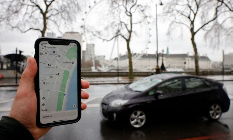 A man poses holding a smartphone showing the App for ride-sharing service Uber in London on March 17, 2021. - US ride-hailing giant Uber won praise Wednesday from Britain's government and trade unions after granting UK drivers worker status with associated rights including a minimum wage, sparking hopes that more technology platforms will follow suit worldwide. (Photo by Tolga Akmen / AFP) (Photo by TOLGA AKMEN/AFP via Getty Images)