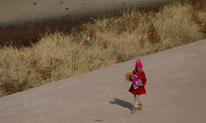 A Venezuelan migrant girl holds a doll while walking on the banks of the Rio Grande in Ciudad Juarez, Chihuahua state, Mexico, on December 27, 2022. - The US government's two-year-old policy of invoking Covid-19 precautions to turn away hundreds of thousands of migrants at the Mexican border will remain in place for now, the Supreme Court ruled Tuesday. The decision to uphold the controversial rule known as Title 42 stemmed off a looming political crisis for President Joe Biden, as thousands waited at the southern border in expectation the policy was about to end. (Photo by Herika Martinez / AFP) (Photo by HERIKA MARTINEZ/AFP via Getty Images)