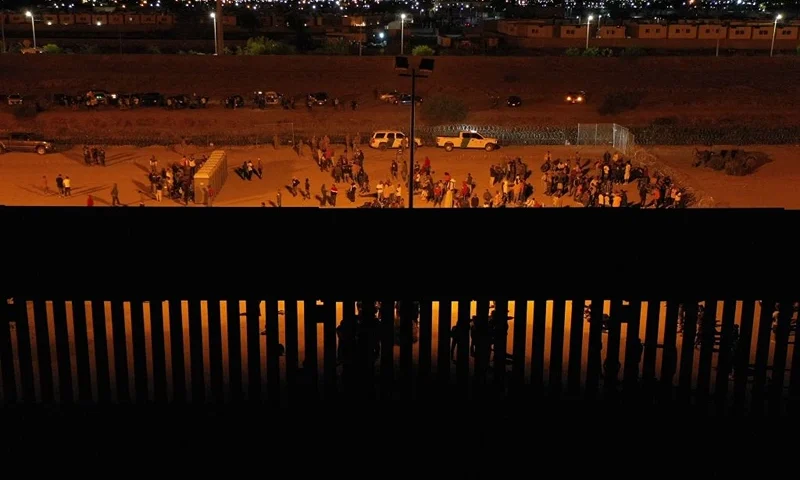 Migrants wait at night along the border wall to surrender to US Customs and Border Protection (CBP) Border Patrol agents for immigration and asylum claim processing before the expiration of Title 42 upon crossing the Rio Grande river from Ciudad Juarez (TOP) into the United States on the US-Mexico border in El Paso, Texas on May 11, 2023. Covid-era rules that have prevented hundreds of thousands of people from claiming asylum at the southern US border expired early on May 11, 2023, creating uncertainty for migrants and setting off a political firestorm. The government of President Joe Biden says it is trying to balance a humane system of offering refuge to those in need with one that will prevent an uncontrollable spike in arrivals. (Photo by Patrick T. Fallon / AFP) (Photo by PATRICK T. FALLON/AFP via Getty Images)