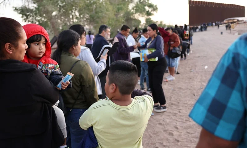 A Peruvian family (L) and other immigrants seeking asylum in the United States wait in line to be processed by U.S. Border Patrol agents after crossing into Arizona from Mexico on May 11, 2023 in Yuma, Arizona. A surge of immigrants is expected with today's end of the U.S. government's Covid-era Title 42 policy, which for the past three years has allowed for the quick expulsion of irregular migrants entering the country. Over 29,000 immigrants are currently in the custody of U.S. Customs and Border Protection ahead of the sunset of the policy tonight. (Photo by Mario Tama/Getty Images)