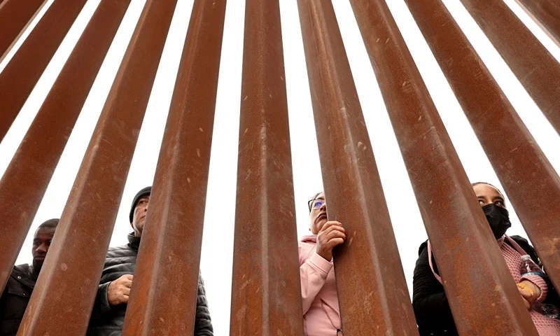 SAN DIEGO, CALIFORNIA - MAY 13: Immigrants seeking asylum in the U.S., who are stuck in a makeshift camp amongst the border walls between the U.S. and Mexico, look through the border wall on May 13, 2023 in San Diego, California. Some of the hundreds of migrants at the open-air camp have been waiting for days in limbo for a chance to plead for asylum, as local volunteer groups are providing food and other necessities. The U.S. government's Covid-era Title 42 policy, which for the past three years had allowed for the quick expulsion of irregular migrants entering the country, expired in the evening on May 11th. (Photo by Mario Tama/Getty Images)