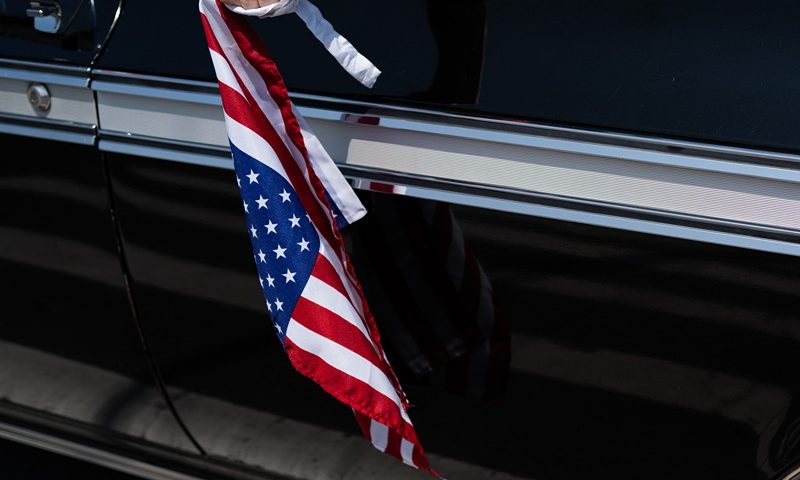 A woman holds an American flag while in a car procession during the 104th annual Memorial Day parade on May 29, 2023 in the Staten Island borough of New York City. Dozens of veterans, local politicians, cars and nearly 50 motorcycles joined the parade. The U.S. celebrates Memorial Day each year to honor those who have died while serving in the Armed Forces. (Photo by Spencer Platt/Getty Images)