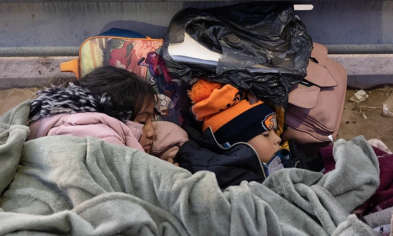 EL PASO, TEXAS - DECEMBER 22: Children from Colombia sleep while spending the night camped with their family alongside the U.S.-Mexico border fence on December 22, 2022 in El Paso, Texas. A spike in the number of migrants seeking asylum in the United States has challenged local, state and federal authorities. The numbers are expected to increase as the fate of the Title 42 authority to expel migrants remains in limbo pending a Supreme Court decision expected after Christmas. (Photo by John Moore/Getty Images)