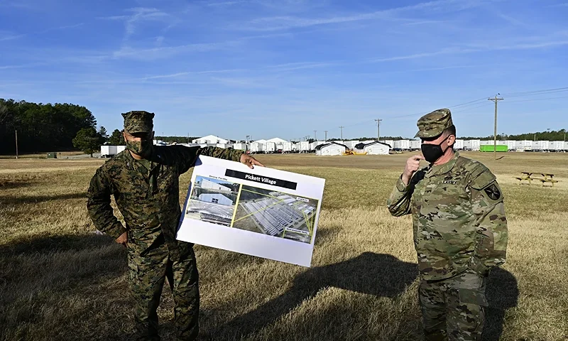 BLACKSTONE, VA - DECEMBER 16: Col. Quintin Jones (L) of the US Marine Corps and Brig. General Paul Craft (R) of the US Army hold a poster describing the now-empty nearby Pickett Village, an Afghan refugee camp at Fort Pickett on December 16, 2021 in Blackstone, Virginia. Fort Pickett normally operates as an Army National Guard maneuver training center, but converted its capabilities to house up to 10,000 Afghan refugees as of August 28, 2020. Approximately 5,500 refugees have been resettled in permanent housing, and the camp is beginning the process of being descoped as Operation Allies Welcome comes to a close. (Photo by Jon Cherry/Getty Images)