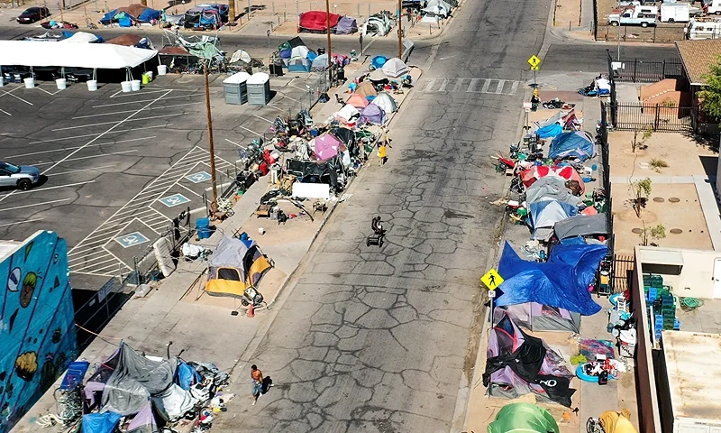 PHOENIX, ARIZONA - JULY 21: An aerial view of people walking past a homeless encampment in the afternoon heat on July 21, 2022 in Phoenix, Arizona. The National Weather Service issued an excessive heat warning for eight counties in Arizona including Maricopa County today. Heat-associated deaths in Maricopa County hit a new half-year record amid an increase in unhoused people living outdoors in Phoenix. According to the Maricopa County Department of Health, there were 17 confirmed heat-associated deaths in the first six months of 2022 with 126 more under investigation. (Photo by Mario Tama/Getty Images)