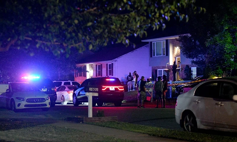 Police and a crowd are seen outside a home where multiple people were shot in Annapolis, Md., on Sunday, June 11, 2023. (Paul W. Gillespie/The Baltimore Sun via AP)