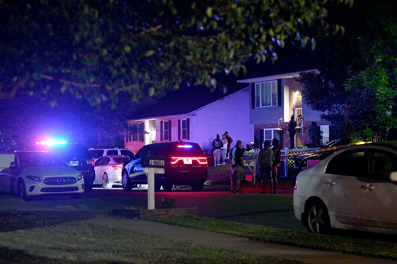 Police and a crowd are seen outside a home where multiple people were shot in Annapolis, Md., on Sunday, June 11, 2023. (Paul W. Gillespie/The Baltimore Sun via AP)