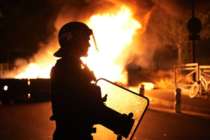 TOPSHOT - A firefighter looks on as vehicles burn following riots in Nanterre, west of Paris, on June 28, 2023, a day after a 17-year-old boy was shot in the chest by police at point-blank range in this western suburb of Paris. Violent protests broke out in France in the early hours of June 29, 2023, as anger grows over the police killing of a teenager, with security forces arresting 150 people in the chaos that saw balaclava-clad protesters burning cars and setting off fireworks. Nahel M., 17, was shot in the chest at point-blank range on June 27, 2023, morning in an incident that has reignited debate in France about police tactics long criticised by rights groups over the treatment of people in low-income suburbs, particularly ethnic minorities. (Photo by Zakaria ABDELKAFI / AFP) (Photo by ZAKARIA ABDELKAFI/AFP via Getty Images)