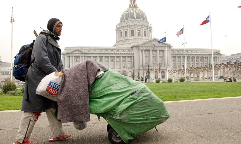 SAN FRANCISCO, CA - DECEMBER 6: Robert Rey, a homeless man, pushes his belongings past San Francisco City Hall December 6, 2002 in San Francisco, California. San Francisco has attracted increasing numbers of homeless people in recent years. Official estimates tally homeless in the area to more than 12,000. Some people believe that the homeless are drawn to the area, in part, by welfare payments that are far too generous. (Photo by Justin Sullivan/Getty Images)