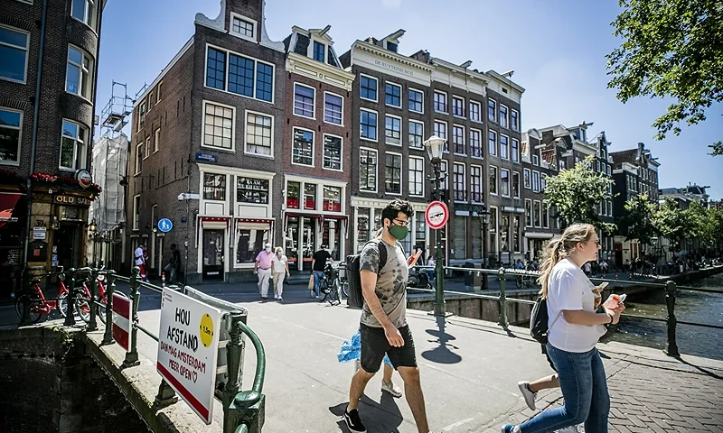 People, wearing a face mask, walk on a bridge of the Red Light district, in Amsterdam on August 5, 2020, as from today, wearing a face mask is mandatory in five usually crowded places in the city of Amsterdam. - France and the Netherlands are gearing up for stricter mask-wearing rules to fight the coronavirus as the global death toll from the pandemic neared 700,000. (Photo by Remko DE WAAL / ANP / AFP) / Netherlands OUT (Photo by REMKO DE WAAL/ANP/AFP via Getty Images)