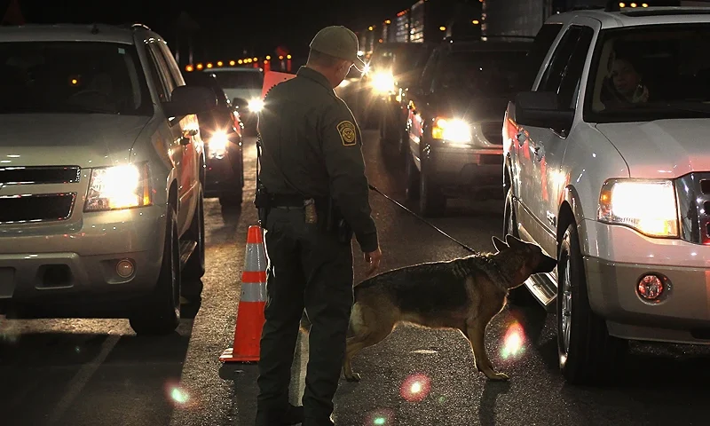 NOGALES, AZ - DECEMBER 07: A border patrol agent and Gitta, a drug-sniffing German shepherd, work a checkpoint on December 7, 2010 north of Nogales, Arizona. The checkpoint falls in the Tucson sector of the U.S.- Mexico border and is considered the most heavily trafficked by illegal immigrants and drug smugglers in the United States. (Photo by John Moore/Getty Images)