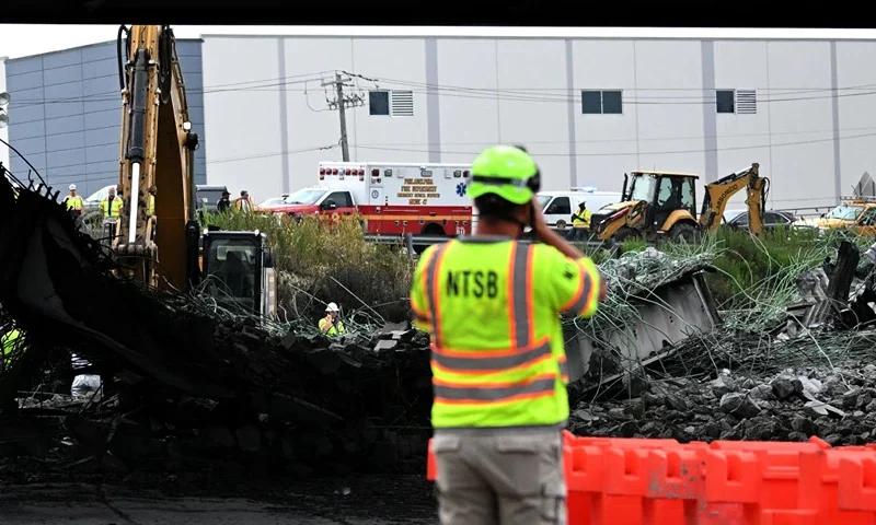 A person with a National Transportation Safety Board vest photographs a section of bridge that collapsed on Interstate 95 after an oil tanker explosion on June 12, 2023 in Philadelphia, Pennsylvania. Traffic was severely affected due to the closure of this primary north-to-south highway for East Coast travel. (Photo by Mark Makela/Getty Images)