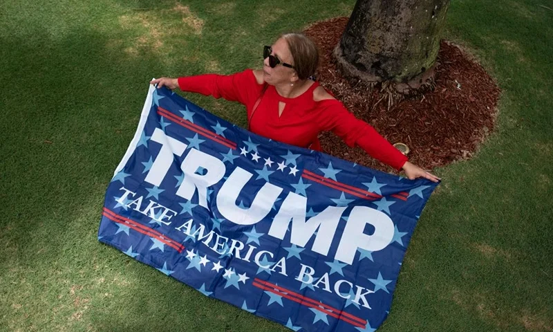 A supporter of former US President Donald Trump sits outside Trump National Doral resort in Doral, Florida, on June 12, 2023. Trump is expected to appear in court in Miami on June 13 for an arraignment regarding 37 federal charges, including violations of the Espionage Act, making false statements, and conspiracy regarding his mishandling of classified material after leaving office. (Photo by Ricardo ARDUENGO / AFP) (Photo by RICARDO ARDUENGO/AFP via Getty Images)