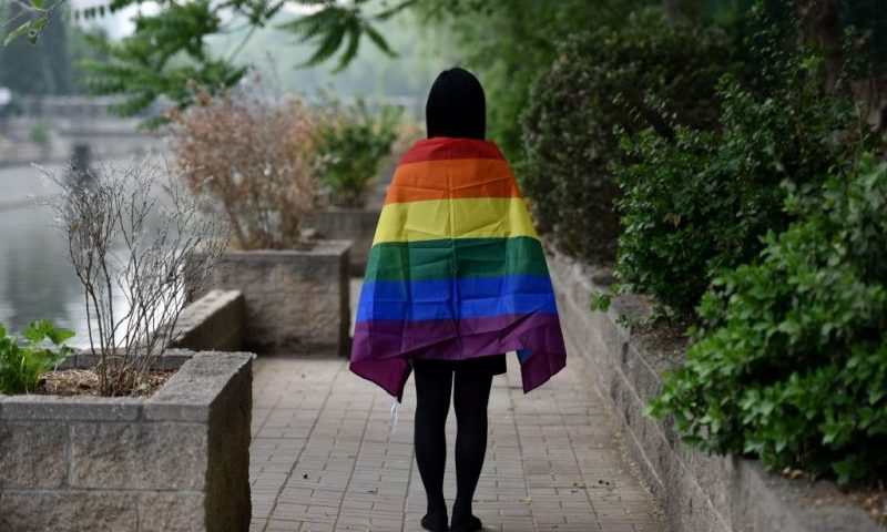 In this photo taken on May 10, 2019, a gay student poses with a rainbow flag in Beijing. - China's LGBT community has had a tough year: Censors have shut down some of its social media forums, online news media have curbed coverage of gay issues, and online shops have removed sales of rainbow-themed products. The tighter restrictions have led the LGBT community in China -- fearing a crackdown -- to prepare for muted celebrations of the International Day Against Homophobia, Transphobia and Biphobia on May 17. (Photo by GREG BAKER / AFP) / TO GO WITH China-gay-rights, FOCUS by Pak YIU (Photo credit should read GREG BAKER/AFP via Getty Images)