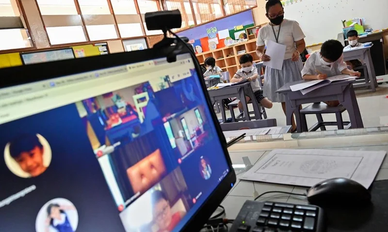 This photo taken on June 25, 2020 shows a teacher attending to students in a classroom and online at the International Pioneers School in Bangkok, after the school reopened following its temporary closure due to concerns over the spread of the COVID-19 novel coronavirus. - Children across Thailand, some of whom have been kept at home under self-quarantine by their parents due to coronavirus fears, have now returned to their classrooms as all schools reopen in the country, though authorities recommended that class sizes be restricted to 20-25 students while doorknobs, desks and other areas at risk of spreading infection be sanitised frequently throughout the day. (Photo by Romeo GACAD / AFP) (Photo by ROMEO GACAD/AFP via Getty Images)