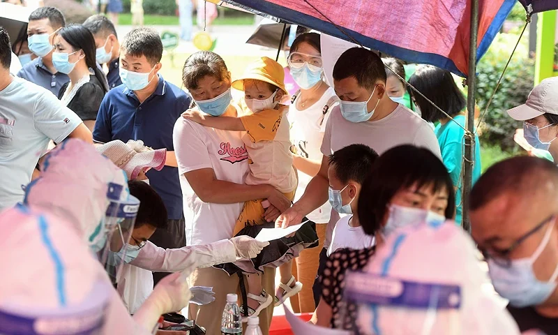 TOPSHOT - Residents queue to take nucleic acid tests for the coronavirus in Wuhan in China's central Hubei province on August 3, 2021, as the city tests its entire population for Covid-19. - China OUT (Photo by AFP) / China OUT (Photo by STR/AFP via Getty Images)