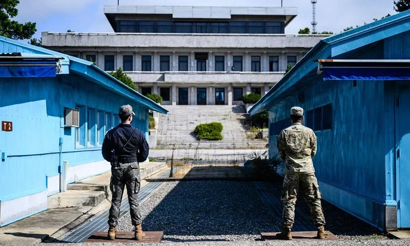 UNC (United Nations Command) soldiers (R) and a South Korean soldier (L) stand guard before North Korea's Panmon Hall (rear C) and the military demarcation line separating North and South Korea, at the Joint Security Area (JSA) of the Demilitarized Zone (DMZ) in the truce village of Panmunjom on October 4, 2022. - North Korea fired a mid-range ballistic missile on October 4, which flew over Japan, Seoul and Tokyo said, a significant escalation as Pyongyang ramps up its record-breaking weapons-testing blitz. (Photo by ANTHONY WALLACE / AFP) (Photo by ANTHONY WALLACE/AFP via Getty Images)