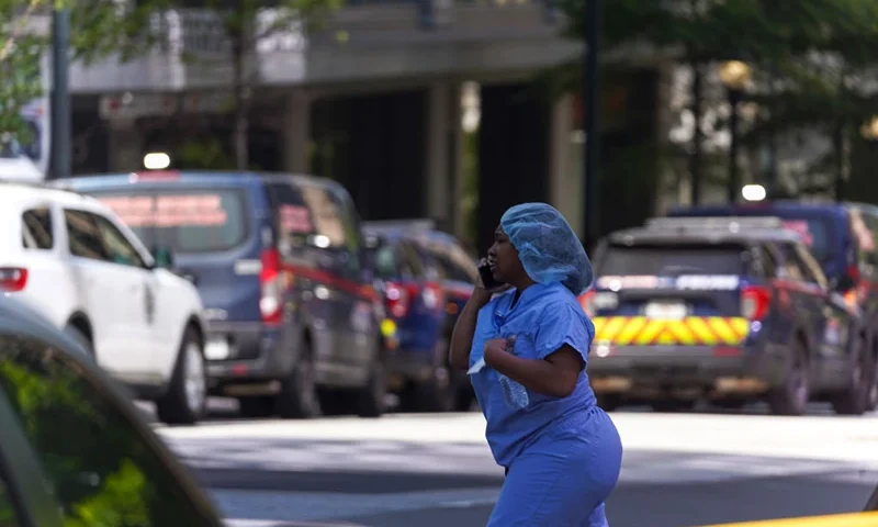ATLANTA, GA - MAY 3: A woman in scrubs talks on the phone as police officers work the scene of a shooting at a Northside Hospital medical facility on May 3, 2023 in Atlanta, Georgia. Police say one person was killed and four others injured in the shooting and the suspect is still at large. (Photo by Megan Varner/Getty Images)