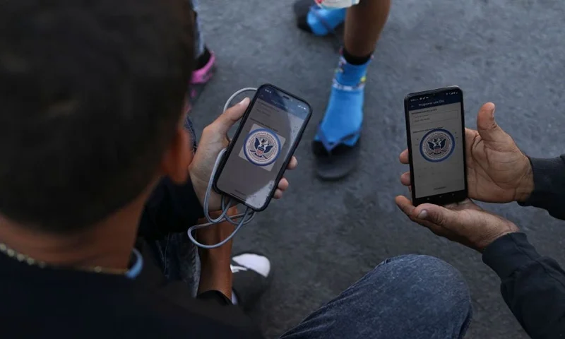 Venezuelan migrants browse the CBP One mobile app searching for an appointment to enter the United States outside the temporary stay of the National Migration Institute (INM) in Ciudad Juarez, Chihuahua state, Mexico, on May 5, 2023. Under the intense desert sun, among sand and brush, hundreds of migrants crossed the Rio Grande from Mexico on the rumor that the United States would let them in. But their hopes were dashed as they fell prey, once again, to misinformation. Falsehoods and deceptions add to the ordeal of these people, first to reach the border through Mexico and then to obtain asylum in the United States. (Photo by HERIKA MARTINEZ / AFP) (Photo by HERIKA MARTINEZ/AFP via Getty Images)