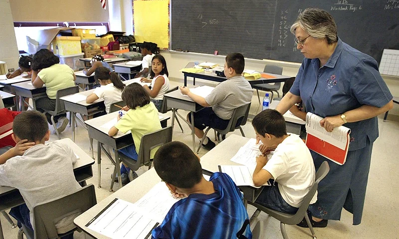 CHICAGO, IL - JULY 2: Teacher Arlene Lebowitz assists a student in her third-grade class during summer school July 2, 2003 in Chicago, Illinois. A record number of students are expected at summer school due to a strong showing for a new voluntary program for mid-tier students and strict application of non-ITBS (Iowa Tests of Basic Skills) test promotion standards. (Photo by Tim Boyle/Getty Images)