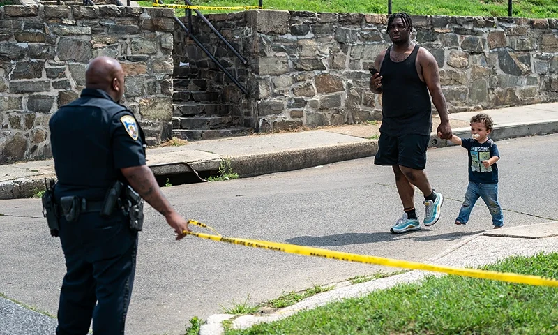 BALTIMORE, MARYLAND - JULY 2: Residents walk through the site of a mass shooting in the Brooklyn Homes neighborhood on July 2, 2023 in Baltimore, Maryland. At least two people were killed and 28 others were wounded during the shooting at a block party on Saturday night. (Photo by Nathan Howard/Getty Images)
