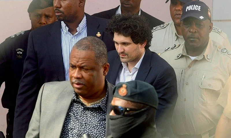 FTX founder Sam Bankman-Fried (C) is led away handcuffed by officers of the Royal Bahamas Police Force at the Nassau, Bahamas, courthouse on December 19, 2022. - Cryptocurrency tycoon Samuel Bankman-Fried arrived at Bahamas magistrate court Monday where he could move to accept extradition to the United States to face charges over the multibillion-dollar collapse of his FTX group. (Photo by Kris INGRAHAM / AFP) (Photo by KRIS INGRAHAM/AFP via Getty Images)