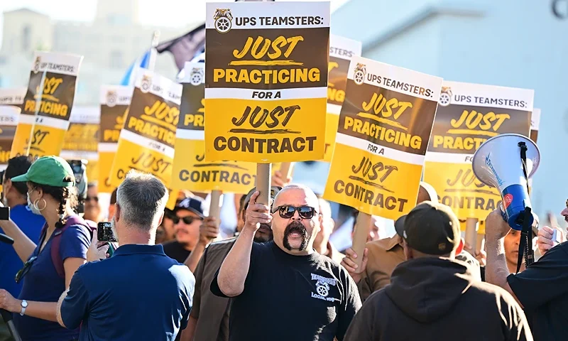UPS workers hold placards at a rally held by the Teamsters Union on July 19, 2023 in Los Angeles, California, ahead of an August 1st deadline for an agreement on a labor contract deal and to avert a strike that could lead to billions of dollars in economic losses. (Photo by Frederic J. BROWN / AFP) (Photo by FREDERIC J. BROWN/AFP via Getty Images)
