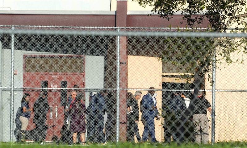 Nine members of Congress and others enter to enter Marjory Stoneman Douglas High School, Friday, Aug. 4, 2023, in Parkland, Fla. The group will tour the blood-stained and bullet-pocked halls, shortly before ballistics technicians reenact the massacre that left 14 students and three staff members dead in 2018. The reenactment is part of a lawsuit filed by the victims' families against former Deputy Scot Peterson and the Broward Sheriff's Office. (AP Photo/Marta Lavandier)