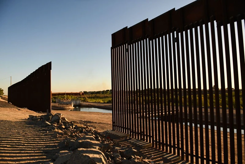 The sun sets behind a gap along the border wall at the Morelos Dam between the US and Mexico in Yuma, Arizona on May 31, 2022. - The stream of impoverished humans flowing into the United States via Mexico runs through the country's public discourse, dividing its politics and coloring relations with nations to the south. The issue of migration is set to loom large at the Summit of the Americas in Los Angeles this week, even without the presence of Mexican President Andres Manuel Lopez Obrador, who is boycoting the meet in protest at the exclusion of Venezuela, Nicaragua and Cuba. (Photo by Patrick T. FALLON / AFP) (Photo by PATRICK T. FALLON/AFP via Getty Images)