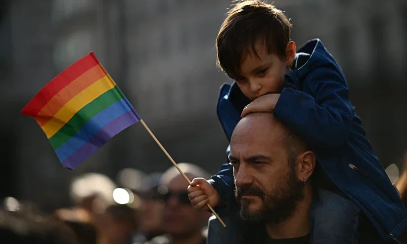 A man carries a boy on his shoulders during a demonstration by gay rights and civil society groups in Milan on March 18, 2023, against moves by Italy's right-wing government to restrict the rights of same-sex parents. (Photo by GABRIEL BOUYS / AFP) (Photo by GABRIEL BOUYS/AFP via Getty Images)