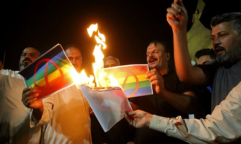IRAQ-SWEDEN-RELIGION-KORAN Supporters of Iraqi Shiite cleric Moqtada Sadr burn posters depicting an LGBTQ+ flag during a protest in Karbala on June 29, 2023, denouncing the burning of the Koran in Sweden. Iraqi protesters breached Sweden's embassy in Baghdad on Thursday, angered by a Koran burning outside a Stockholm mosque that sparked condemnation across the Muslim world. (Photo by Mohammed SAWAF / AFP) (Photo by MOHAMMED SAWAF/AFP via Getty Images)