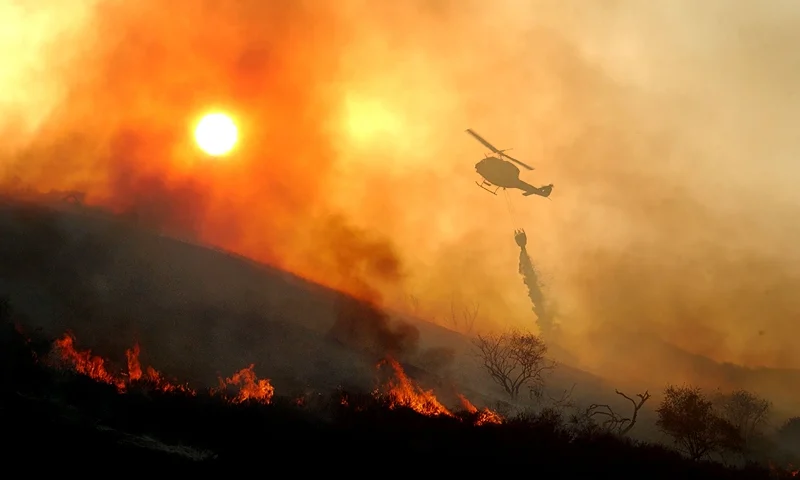 Fire Threatens 200 Homes in California 405313 05: A helicopter drops water on a wildfire as the sun sets May 13, 2002 near Rancho Santa Margarita, CA. The fire consumed about 1,100 acres in less than six hours and seriously threatened 200 homes. Because the region is experiencing what may be the dryest season on record, native vegatation has a very low moisture content causing the official fire season to begin about six weeks earlier than usual. An extremely dangerous fire season is widely predicted for southern California this year. (Photo by David McNew/Getty Images)