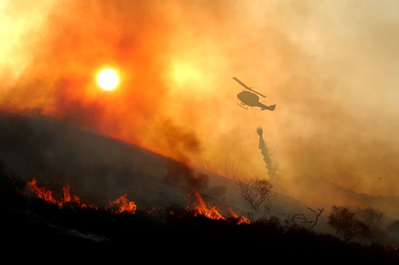 Fire Threatens 200 Homes in California
405313 05: A helicopter drops water on a wildfire as the sun sets May 13, 2002 near Rancho Santa Margarita, CA. The fire consumed about 1,100 acres in less than six hours and seriously threatened 200 homes. Because the region is experiencing what may be the dryest season on record, native vegatation has a very low moisture content causing the official fire season to begin about six weeks earlier than usual. An extremely dangerous fire season is widely predicted for southern California this year. (Photo by David McNew/Getty Images)