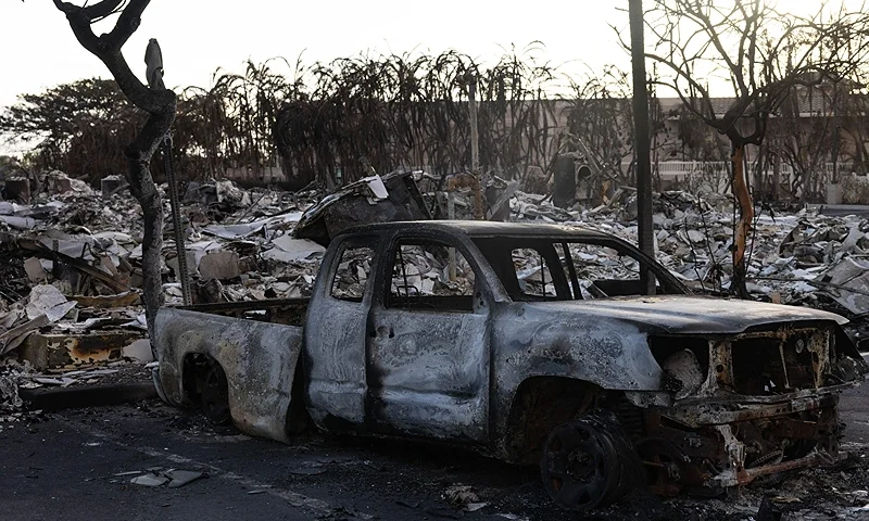 A burnt out car lies in the driveway of charred apartment complex in the aftermath of a wildfire in Lahaina, western Maui, Hawaii on August 12, 2023. Hawaii's Attorney General, Anne Lopez, said August 11, she was opening a probe into the handling of devastating wildfires that killed at least 80 people in the state this week, as criticism grows of the official response. The announcement and increased death toll came as residents of Lahaina were allowed back into the town for the first time. (Photo by Yuki IWAMURA / AFP) (Photo by YUKI IWAMURA/AFP via Getty Images)