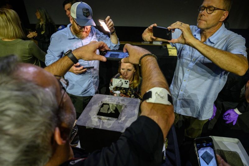 TOPSHOT - People gather around a nearly 200-year-old time capsule during a ceremony in the Robinson Auditorium at Thayer Hall of the US Military Academy in West Point, New York, on August 28, 2023. The sealed lead time capsule measuring about one square foot was discovered in the Thaddeus Kosciuszko monument's base during recent renovations. Academy officials determined the capsule was placed in the base of the Kosciuszko monument 26 years after the academy's founding by cadets in 1828. The capsule was found to be mostly empty other than grey sediment. (Photo by Ed JONES / AFP) (Photo by ED JONES/AFP via Getty Images)