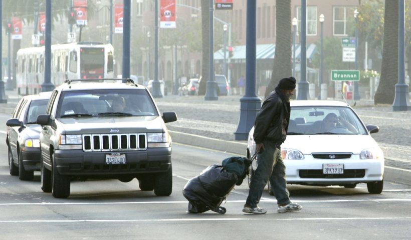 SAN FRANCISCO, CA - DECEMBER 5: Maceo Grigsby, a homeless man, pulls his belongings behind him as he crosses a street December 5, 2002 in San Francisco, California. San Francisco has attracted increasing numbers of homeless people in recent years. Official estimates tally homeless in the area to more than 12,000. Some people believe that the homeless are drawn to the area, in part, by welfare payments that are far too generous. (Photo by Justin Sullivan/Getty Images)