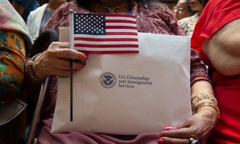 A woman holds the flag and her paperwork as the US Citizenship and Immigration Services welcomes 200 new citizens from 50 countries during a ceremony in honor of Independence Day at the New York Public Library on July 3, 2018 in New York. (Photo by Bryan R. Smith / AFP) (Photo credit should read BRYAN R. SMITH/AFP via Getty Images)