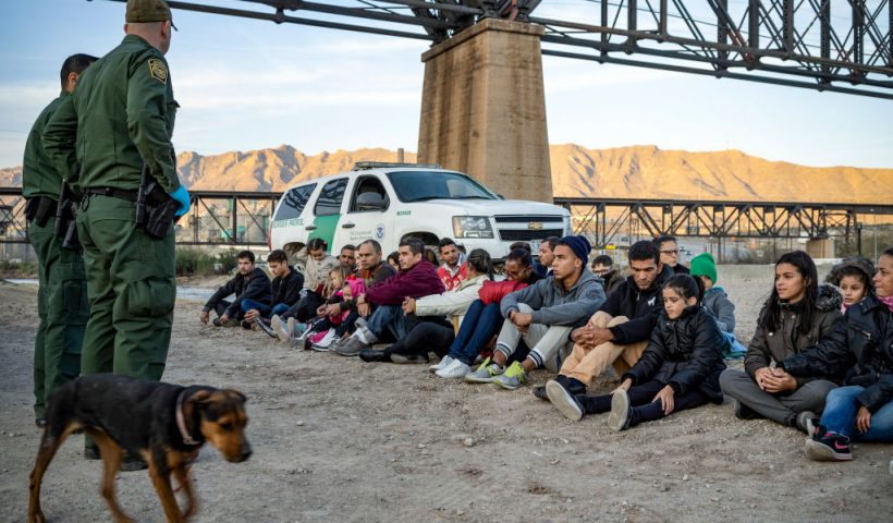 TOPSHOT - A group of about 30 Brazilian migrants, who had just crossed the border, sit on the ground near US Border Patrol agents, on the property of Jeff Allen, who used to run a brick factory near Mt. Christo Rey on the US-Mexico border in Sunland Park, New Mexico on March 20, 2019. - The militia members say they will patrol the US-Mexico border near Mt. Christo Rey, "Until the wall is built." In recent months, thousands of Central Americans have arrived in Mexico in several caravans in the hope of finding a better life in the United States. US President Donald Trump has branded such migrants a threat to national security, demanding billions of dollars from Congress to build a wall on the southern US border. (Photo by Paul Ratje / AFP) (Photo credit should read PAUL RATJE/AFP via Getty Images)