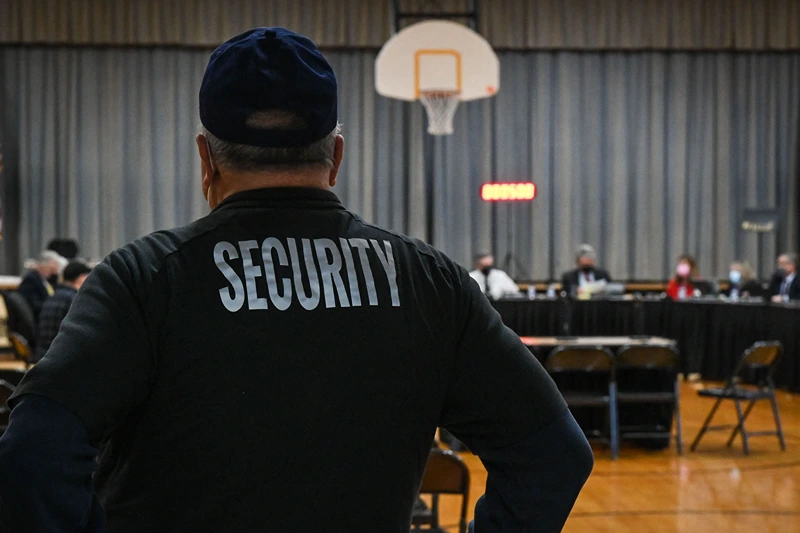A Pennsbury School District security guard observes a Pennsbury School Board meeting in Levittown, Pennsylvania on December 16, 2021. - As Joshua Waldorf was running for a third term on the Pennsbury school board in November, one particularly heated debate triggered a flood of vitriolic messages to his inbox -- one of them urging him to shoot himself. In a shift mirrored in cities across America, his local council overseeing schools in the leafy suburbs of Philadelphia had unwittingly become a battleground in the politicized culture wars roiling the nation. The hateful messages aimed at Waldorf were just one example of the flow of anonymous slurs and threats directed at him and fellow members of the nine-seat board in past months -- as their once studious meetings turned to angry shouting matches. (Photo by Kylie COOPER / AFP) (Photo by KYLIE COOPER/AFP via Getty Images)
