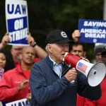 TOPSHOT-US-POLITICS-AUTOMOBILE-UNIONS-STRIKE-BIDEN-economy-labou TOPSHOT - US President Joe Biden addresses striking members of the United Auto Workers (UAW) union at a picket line outside a General Motors Service Parts Operations plant in Belleville, Michigan, on September 26, 2023. Some 5,600 members of the UAW walked out of 38 US parts and distribution centers at General Motors and Stellantis at noon September 22, 2023, adding to last week's dramatic worker walkout. According to the White House, Biden is the first sitting president to join a picket line. (Photo by Jim WATSON / AFP) (Photo by JIM WATSON/AFP via Getty Images)