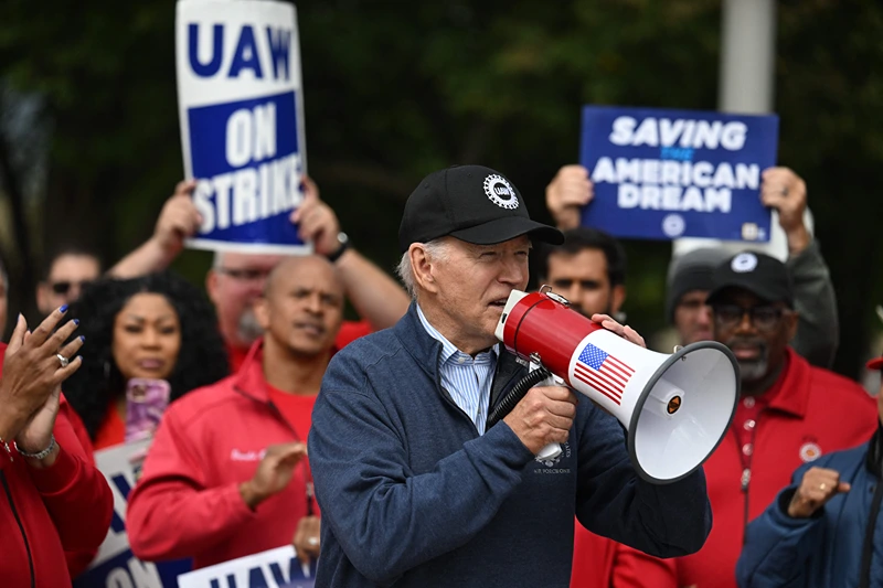 TOPSHOT-US-POLITICS-AUTOMOBILE-UNIONS-STRIKE-BIDEN-economy-labou
TOPSHOT - US President Joe Biden addresses striking members of the United Auto Workers (UAW) union at a picket line outside a General Motors Service Parts Operations plant in Belleville, Michigan, on September 26, 2023. Some 5,600 members of the UAW walked out of 38 US parts and distribution centers at General Motors and Stellantis at noon September 22, 2023, adding to last week's dramatic worker walkout. According to the White House, Biden is the first sitting president to join a picket line. (Photo by Jim WATSON / AFP) (Photo by JIM WATSON/AFP via Getty Images)