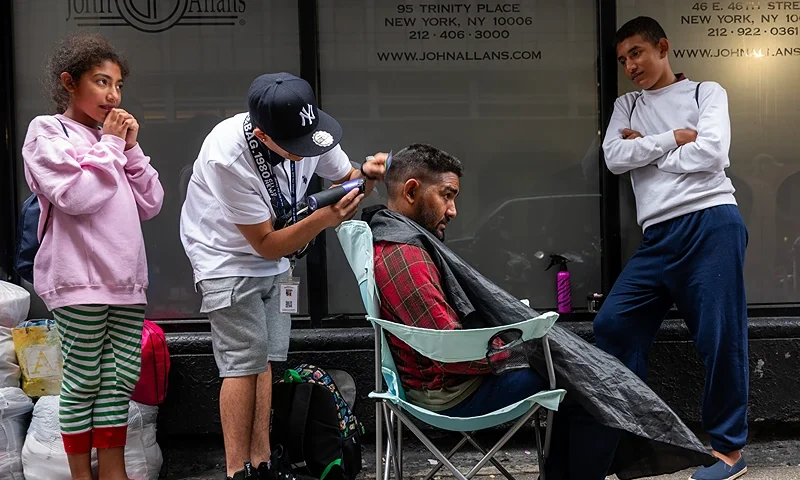 NEW YORK, NEW YORK - SEPTEMBER 28: Jose, a recently arrived migrant from Venezuela, gets his haircut on the street outside of the Roosevelt Hotel in midtown Manhattan on September 28, 2023 in New York City. Thousands of migrants, many from Central America, continue to arrive into New York monthly as the city struggles to feed and house as of the new arrivals. The situation has caused tension between local politicians and communities where the migrants are being sheltered. Immigration and border security are once again becoming dominant issues as America heads towards a presidential election in 2024. (Photo by Spencer Platt/Getty Images)