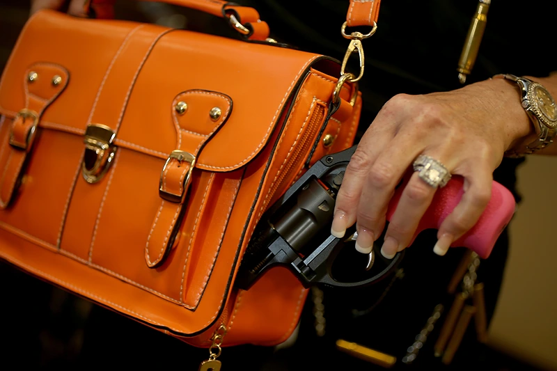 Florida Entrepreneur Creates Gun Fashion Line For Women
BOCA RATON, FL - OCTOBER 21: Susan Kushlin poses with a concealed-carry handbag that her company, Gun Girls, Inc., created for women that enjoy guns on October 21, 2013 in Boca Raton, Florida. Her line includes bullet jewelry, handbags, belts and custom logo apparel with some of the items priced at $35 gold-toned bullet belts, $20 dangling gun earrings, $76 pink concealed-carry handbags and $21 rhinestone-studded tank tops. (Photo by Joe Raedle/Getty Images)