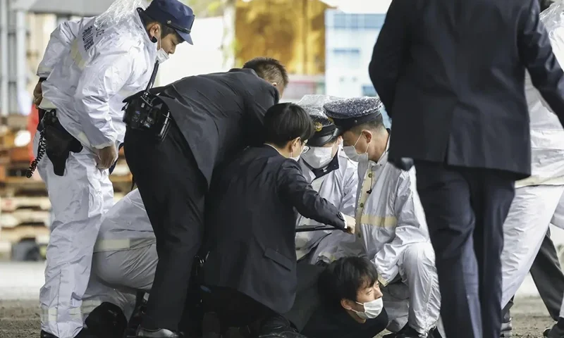 A man believed to be a suspect, center on the ground, is caught by police after he allegedly threw “the suspicious object,” as Japanese Prime Minister Fumio Kishida visited Saikazaki port for an election campaign event in Wakayama, western Japan Saturday, April 15, 2023. Kishida was evacuated unharmed Saturday after someone threw an explosive device in his direction while he was campaigning at the fishing port in western Japan, officials said.(Kyodo News via AP)