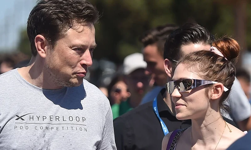 SpaxeX founder Elon Musk (L) and Canadian musician Grimes (Claire Boucher) attend the 2018 Space X Hyperloop Pod Competition, in Hawthorne, California on July 22, 2018. - Students from colleges and universities from the US and around the world are taking part in testing their pods on a 1.25 kilometer-long (0.75-mile) tubular test track at the SpaceX headquarters. (Photo by Robyn Beck / AFP) (Photo credit should read ROBYN BECK/AFP via Getty Images)