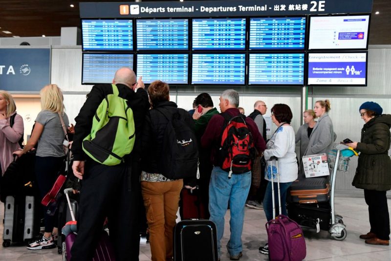 Travellers look at screens displaying departures flights at Paris-Charles-de-Gaulle airport after a US 30-day ban on travel from Europe due to the COVID-19 spread in Roissy-en-France on March 12, 2020. - US President Donald Trump announced on March 11, 2020 a shock 30-day ban on travel from mainland Europe over the coronavirus pandemic that has sparked unprecedented lockdowns, widespread panic and another financial market meltdown. (Photo by Bertrand GUAY / AFP) (Photo by BERTRAND GUAY/AFP via Getty Images)