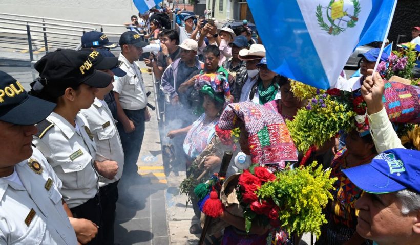 Police officers stand guard as indigenous women burn incense outside the Constitutional Court during the "March of the Flowers" to demand the resignation of judicial officials accused of generating an electoral crisis in Guatemala ahead of a runoff vote, in Guatemala City on July 23, 2023. Guatemala has been rocked for weeks by legal actions targeting the Semilla (Seed) party of Bernardo Arevalo -- one of the two presidential candidates to emerge from a first voting round on June 25. Guatemala's Supreme Electoral Tribunal (TSE) on Friday urged the country's highest court to intervene for free and fair presidential elections in the August 20 runoff vote even as investigators raided Semilla's headquarters. (Photo by Johan ORDONEZ / AFP) (Photo by JOHAN ORDONEZ/AFP via Getty Images)