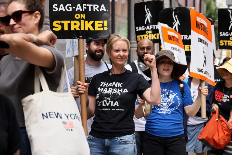 NEW YORK, NEW YORK - JULY 21: Cynthia Nixon (C) joins SAG-AFTRA members on the picket line outside of Netflix and Warner Bros on July 21, 2023 in New York City. Members of SAG-AFTRA, Hollywood's largest union which represents actors and other media professionals, have joined striking WGA (Writers Guild of America) workers in the first joint walkout against the studios since 1960. The strike could shut down Hollywood productions completely with writers in the third month of their strike against the Hollywood studios.  (Photo by Dia Dipasupil/Getty Images)