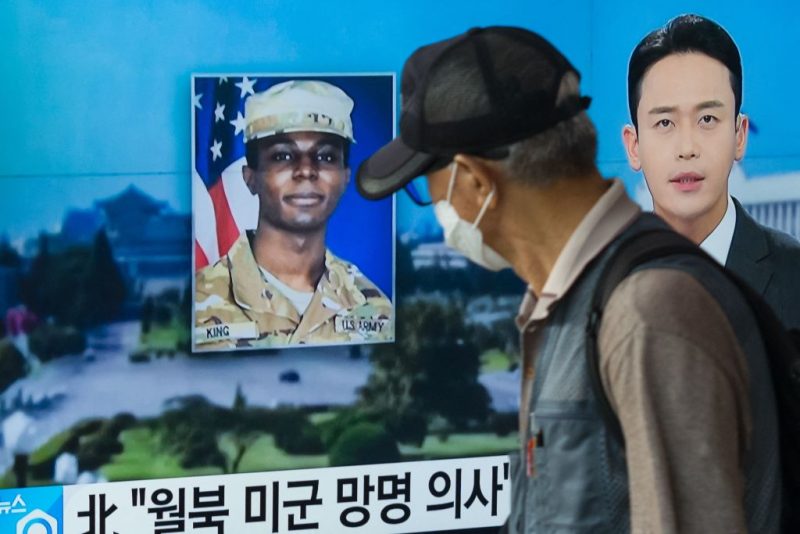 In this photo taken in Seoul on August 16, 2023, a man walks past a television showing a news broadcast featuring a photo of US soldier Travis King (C), who ran across the border into North Korea while part of a tour group visiting the Demilitarized Zone on South Korea's border on July 18. Travis King defected to North Korea to escape 