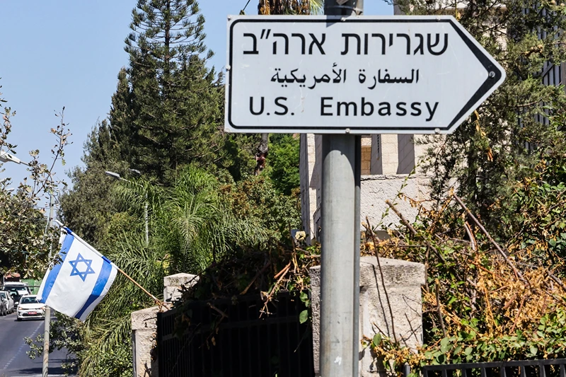 ISRAEL-PALESTINIAN-US-DIPLOMACY
An Israeli flag is displayed in front of a building near a road sign for the US embassy in Jerusalem on September 27, 2023. The United States said on September 27 it would start letting Israelis visit without visas, after what it said were successful efforts by its ally to address concerns it discriminates against Arab Americans, an assessment contested by some lawmakers. (Photo by Ahmad GHARABLI / AFP) (Photo by AHMAD GHARABLI/AFP via Getty Images)